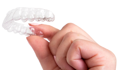 Photo of the a woman's hand holding an invisible teeth aligner similar to Invisalign.