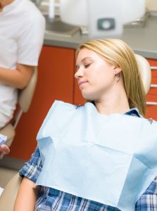 Photo of woman sitting back in a dental chair with her eyes closed; for information on Baton Rouge sedation dentistry during tooth extraction.